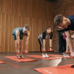 Adults exercising in an indoor fitness class with dumbbells and yoga mats for healthy lifestyle.