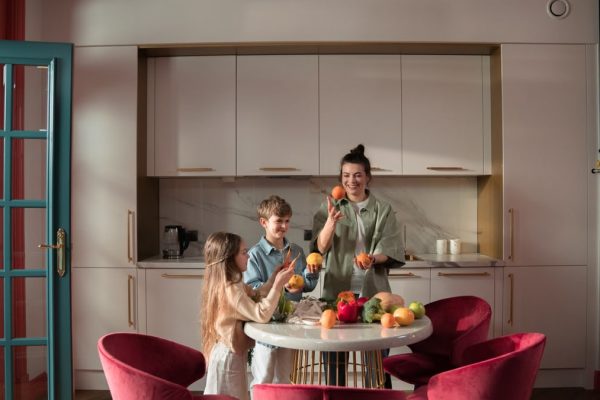 Mother with children preparing meals with fresh ingredients in a modern kitchen.