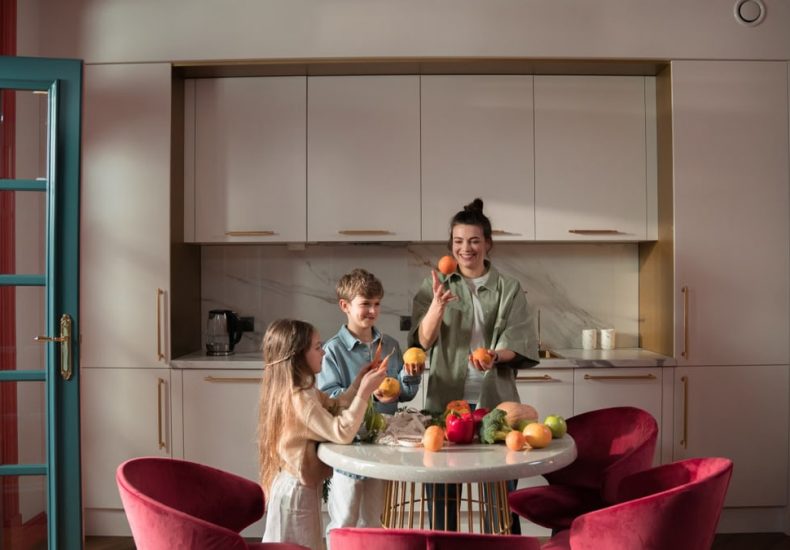 Mother with children preparing meals with fresh ingredients in a modern kitchen.